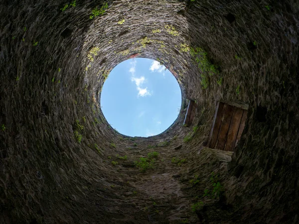 Stone well hole, old construction from inside, brick walls and blue sky background, fall down in the well concept