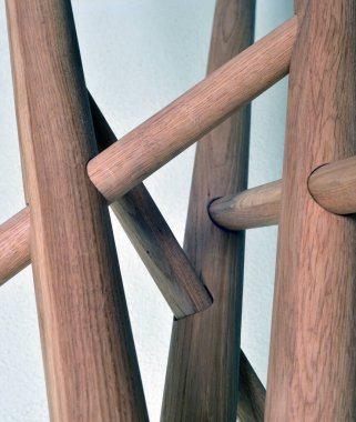 Wooden table legs isolated over gray background, close view photo, crossed star shaped legs, wooden eco furniture elements. Solid wood furniture complicated construction