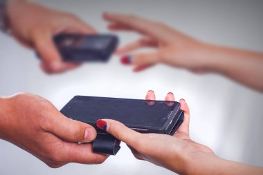 Erkek ve kadın akıllı telefonları değiş tokuş ediyor. Yenilik kavramsal fotoğraf