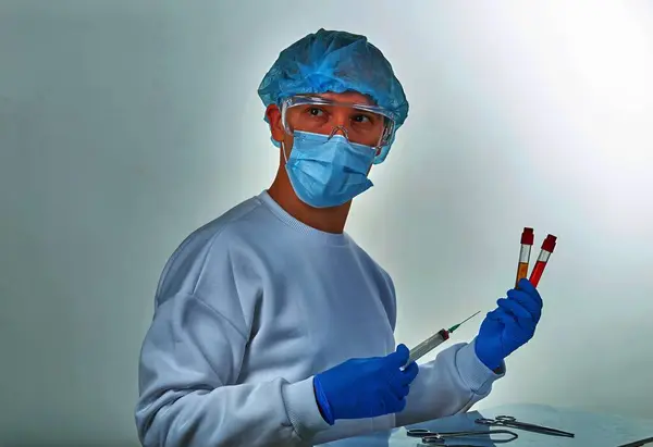 Doctor in mask performing blood test for coronavirus COVID19, HIV, ebola or other dangerous infection. Medical background, instruments, template, wallpaper. Coronavirus disease concept