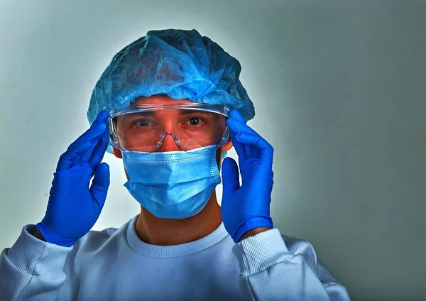 Doctor in mask holding his head, medical background, wallpaper. Coronavirus disease COVID19, hospital, quarantine, analysis concept. Doctor portrait