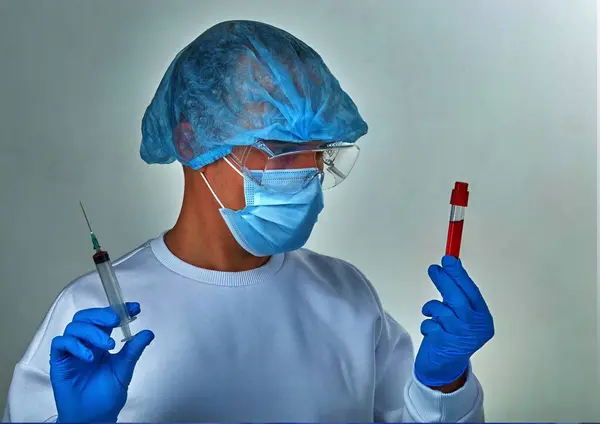 Doctor in mask performing the blood test for coronavirus COVID19, HIV, ebola or other dangerous infection. Medical background, instruments, template, wallpaper. Coronavirus disease concept. Doctor portrait