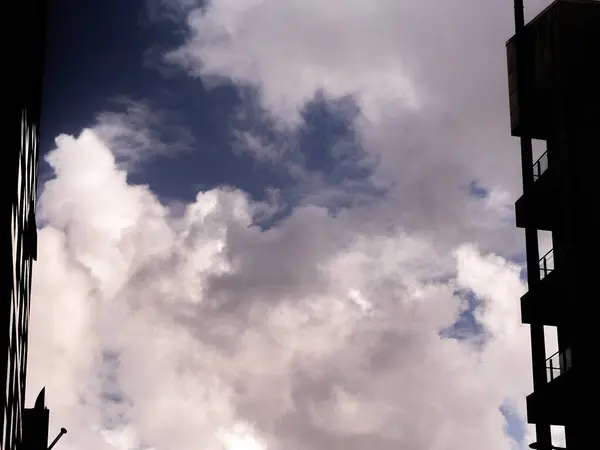 White fluffy clouds between apartment buildings, clouds background
