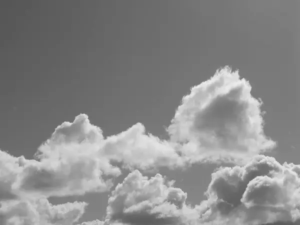 stock image Summer white fluffy cumulus clouds in the deep blue sky. Black and white monochrome grayscale photo