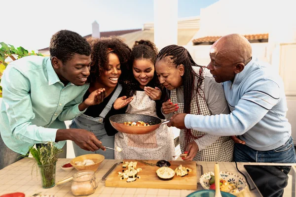 Happy African family preparing food recipe together on house patio