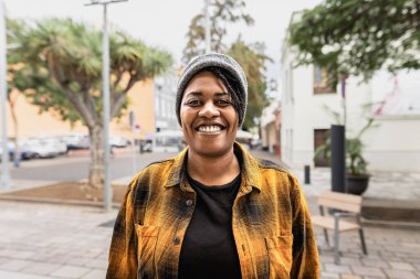 Happy African woman smiling in front of a camera in the city