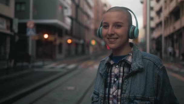 Shaved Head Girl Listening Music Wireless Headphones While Waiting Public — 图库视频影像