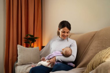 Happy mother taking care of her small baby sleeping in her arms at home - Concept family and motherhood