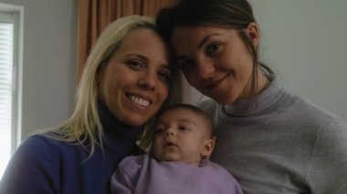 Happy lesbian couple with small baby at home portrait - LGBT family concept