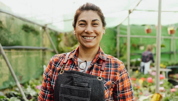 Happy Hispanic woman smiling front of camera while working in flower garden shop