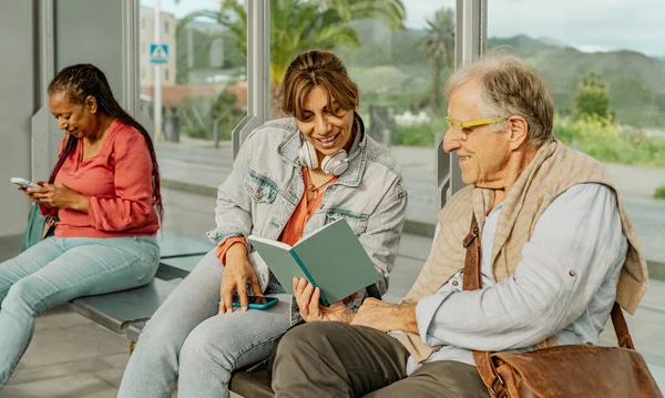 Πολυφυλετικοί Άνθρωποι Διαβάζουν Ένα Βιβλίο Ενώ Περιμένουν Στο Σταθμό Του — Φωτογραφία Αρχείου