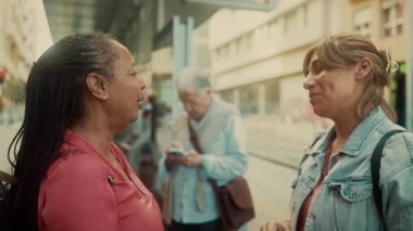 Otobüs durağında bekleyen mutlu çok ırklı bayan arkadaşlar