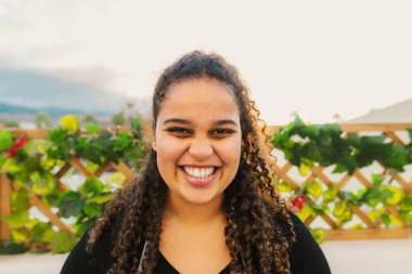 Happy young African girl having fun smiling in front of camera on house patio