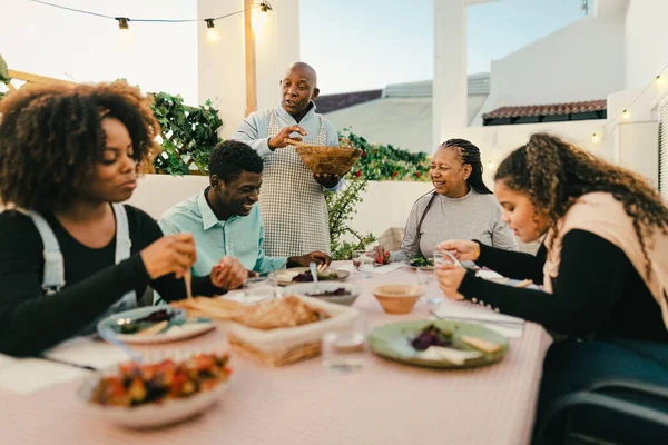 Happy African family dining together on house patio - Family Gatherings concept
