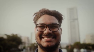 Genç Latin adam şehirde kameranın önünde gülümsüyor.