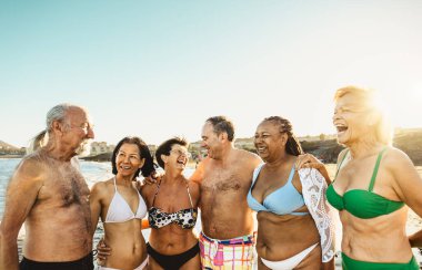 Mutlu çok ırklı kıdemli arkadaşlar yaz tatillerinde sahilde eğleniyorlar - çeşitli yaşlı insanlar tatilden zevk alıyorlar