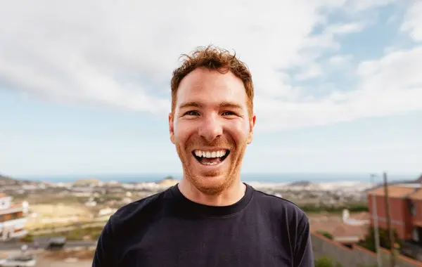 家の屋上でカメラの前で笑っている幸せな白人の若者 ストック画像