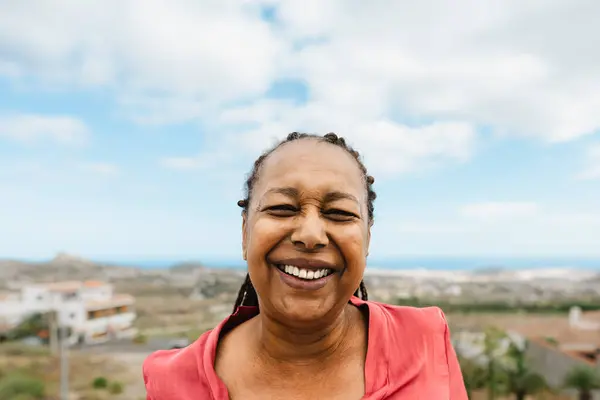 ハッピーシニアアフリカの女性は家の屋上でカメラに笑顔を持っています ロイヤリティフリーのストック写真