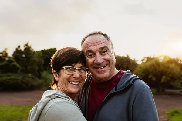 ハッピーシニアカップルは 公共の公園でのワークアウト後のカメラに笑顔を持っています ロイヤリティフリーのストック写真