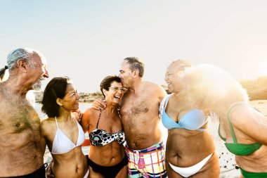 Mutlu çok ırklı kıdemli arkadaşlar yaz tatillerinde sahilde eğleniyorlar - çeşitli yaşlı insanlar tatilden zevk alıyorlar