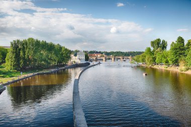 Charles Köprüsü güneşli bir günde Vltava Nehri 'ni geçiyor. Prag, Çek Cumhuriyeti' nin arka planında eski kasaba binaları bulunuyor.