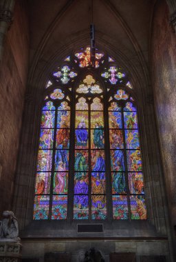 PRAGUE - 11 Mayıs 2024: Çek Cumhuriyeti Prag 'daki St. Vitus Katedrali' nin içindeki dini sahneleri gösteren renkli cam pencereyi aydınlatan güneş ışığı