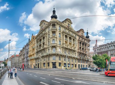 PRAG - 12 Mayıs 2024: Prag, Çek Cumhuriyeti 'nde güneşli bir günün tadını çıkaran turistler, işlek bir caddede tarihi binalar ve tramvayla yürüyor