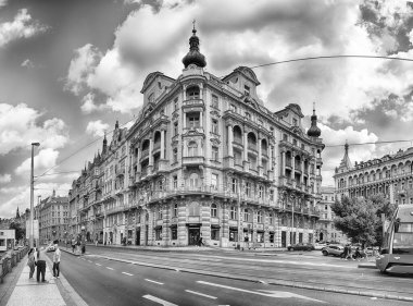 PRAG - 12 Mayıs 2024: Prag, Çek Cumhuriyeti 'nde güneşli bir günün tadını çıkaran turistler, işlek bir caddede tarihi binalar ve tramvayla yürüyor