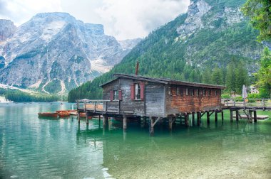 Eski ahşap kayıkhane manzaralı Braies Gölü 'nün sakin sularını yansıtıyor. Arka planda görkemli dolomitler var. Güney Tyrol, İtalya.