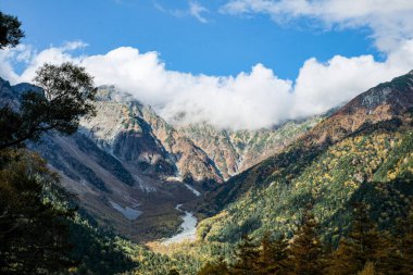 Kamikochi Milli Parkı 'nın arka planında kar dağları, kayalar ve yaprakların renk değiştirdiği tepelerden Azusa nehirleri mevsimi vardı..