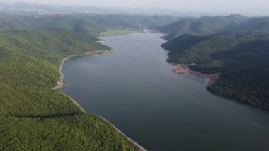 Muak Lek reservoir in Saraburi from aerial bird eye view. Beautiful unseen nature at Muak Lek dam with roadway beside with water and tree hill.