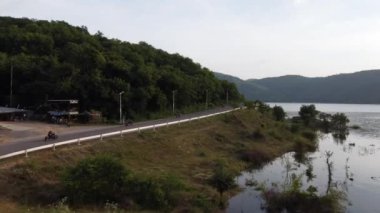 Muak Lek reservoir in Saraburi from aerial bird eye view. Beautiful unseen nature at Muak Lek dam with roadway beside with water and tree hill.