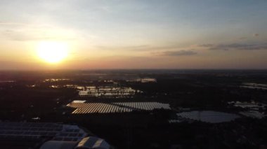 Fly over Solar cells farm beside nature green farm around large industrial factory area. Solar farms are generating renewable energy for the industry. 