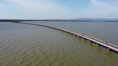 Pa Sak Jolasid barajındaki gölün suyu üzerinde yüzen bir demiryolu köprüsüne parketmiş, Lopburi, Tayland 'da mavi gökyüzü olan inanılmaz bir seyahat treninin havadan görüntüsü..