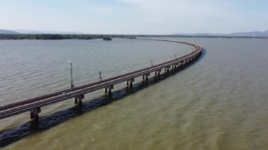 Pa Sak Jolasid barajındaki gölün suyu üzerinde yüzen bir demiryolu köprüsüne parketmiş, Lopburi, Tayland 'da mavi gökyüzü olan inanılmaz bir seyahat treninin havadan görüntüsü..