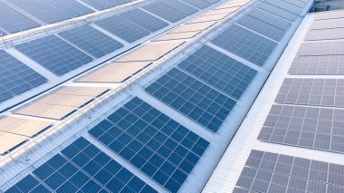 Geleceğin yeşil enerjisi ve sürdürülebilir elektrik kaynağı kavramı. Açık havada güneş panelleri çatılarda ya da İHA 'larla fabrikaların fotovoltaikleri üzerinde yoğunlaşıyor. Mavi tonlu güneş pili ızgaralı endüstriyel çatı.
