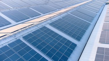 Geleceğin yeşil enerjisi ve sürdürülebilir elektrik kaynağı kavramı. Açık havada güneş panelleri çatılarda ya da İHA 'larla fabrikaların fotovoltaikleri üzerinde yoğunlaşıyor. Mavi tonlu güneş pili ızgaralı endüstriyel çatı.
