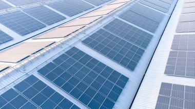 Geleceğin yeşil enerjisi ve sürdürülebilir elektrik kaynağı kavramı. Açık havada güneş panelleri çatılarda ya da İHA 'larla fabrikaların fotovoltaikleri üzerinde yoğunlaşıyor. Mavi tonlu güneş pili ızgaralı endüstriyel çatı.