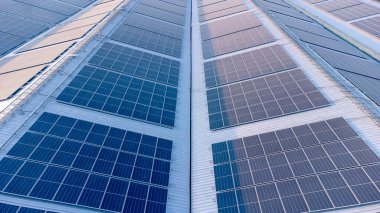 Geleceğin yeşil enerjisi ve sürdürülebilir elektrik kaynağı kavramı. Açık havada güneş panelleri çatılarda ya da İHA 'larla fabrikaların fotovoltaikleri üzerinde yoğunlaşıyor. Mavi tonlu güneş pili ızgaralı endüstriyel çatı.