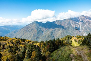 Ana turistik ilgi odağı Shin Hotaka 'nın sonbahar renklerinde bir teleferik ve turistlere hizmet veren bir halatla. Japon Alpleri, Shinhotaka halatı ve sonbahar yaprakları..