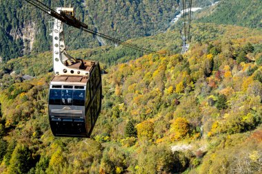 Ana turistik ilgi odağı Shin Hotaka 'nın sonbahar renklerinde bir teleferik ve turistlere hizmet veren bir halatla. Japon Alpleri, Shinhotaka halatı ve sonbahar yaprakları..