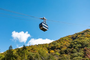 Ana turistik ilgi odağı Shin Hotaka 'nın sonbahar renklerinde bir teleferik ve turistlere hizmet veren bir halatla. Japon Alpleri, Shinhotaka halatı ve sonbahar yaprakları..