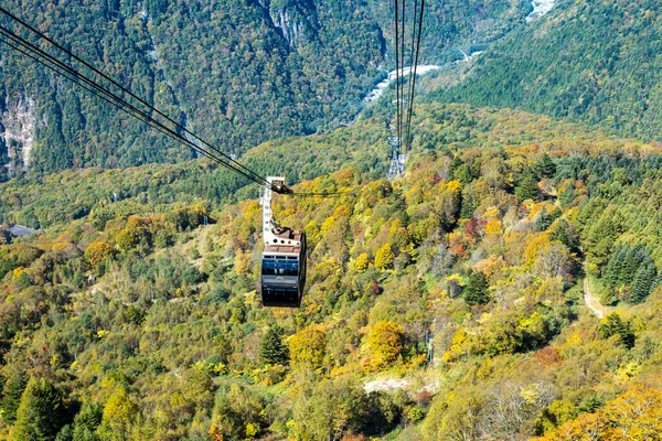 Ana turistik ilgi odağı Shin Hotaka 'nın sonbahar renklerinde bir teleferik ve turistlere hizmet veren bir halatla. Japon Alpleri, Shinhotaka halatı ve sonbahar yaprakları..