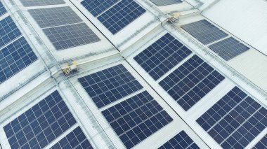 Bir binanın çatısına birden fazla güneş paneli yerleştirildi. Güneş panelleri düzenli sıra ve sütunlar halinde düzenlenir, her panel arasında net ayrılıklar bulunur. 