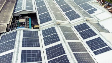 Bir binanın çatısına birden fazla güneş paneli yerleştirildi. Güneş panelleri düzenli sıra ve sütunlar halinde düzenlenir, her panel arasında net ayrılıklar bulunur. 