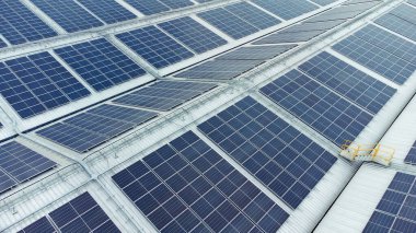 Bir binanın çatısına birden fazla güneş paneli yerleştirildi. Güneş panelleri düzenli sıra ve sütunlar halinde düzenlenir, her panel arasında net ayrılıklar bulunur. 