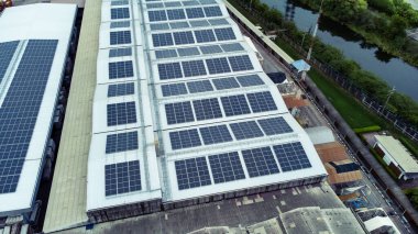 Bir binanın çatısına birden fazla güneş paneli yerleştirildi. Güneş panelleri düzenli sıra ve sütunlar halinde düzenlenir, her panel arasında net ayrılıklar bulunur. 