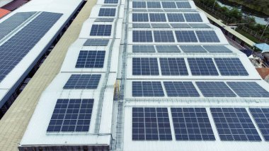 Bir binanın çatısına birden fazla güneş paneli yerleştirildi. Güneş panelleri düzenli sıra ve sütunlar halinde düzenlenir, her panel arasında net ayrılıklar bulunur. 