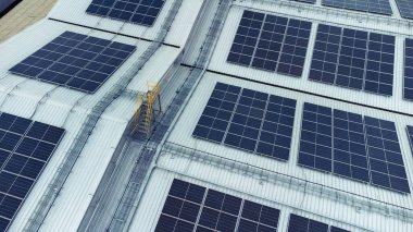 Bir binanın çatısına birden fazla güneş paneli yerleştirildi. Güneş panelleri düzenli sıra ve sütunlar halinde düzenlenir, her panel arasında net ayrılıklar bulunur. 