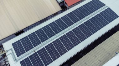 Bir binanın çatısına birden fazla güneş paneli yerleştirildi. Güneş panelleri düzenli sıra ve sütunlar halinde düzenlenir, her panel arasında net ayrılıklar bulunur. 